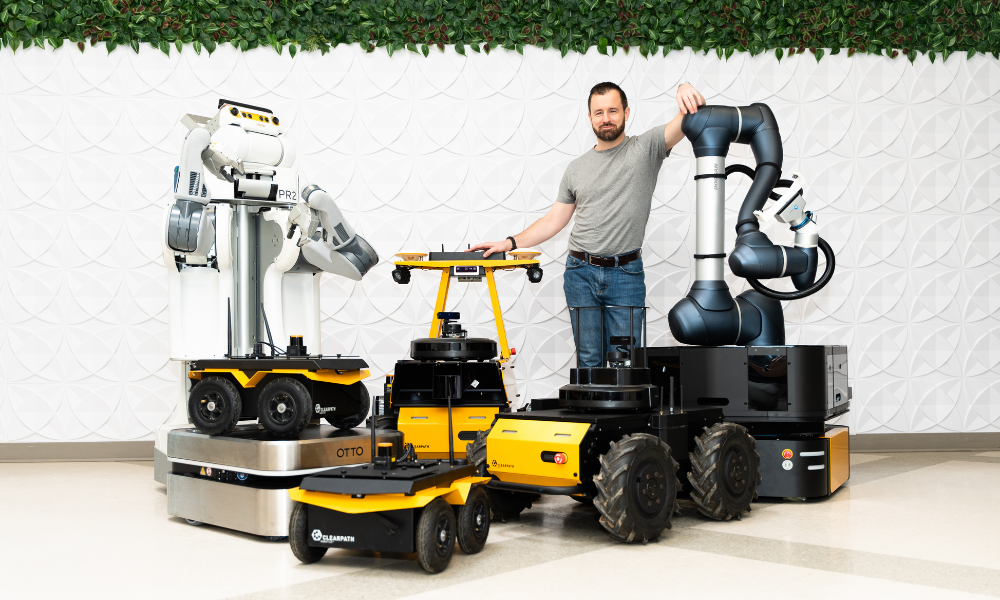 Ryan Gariepy standing with Clearpath robots