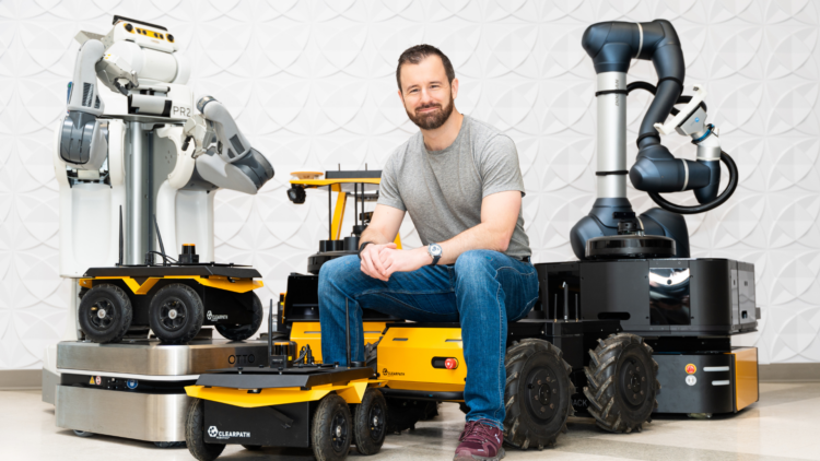 Ryan Gariepy sitting with Clearpath robots