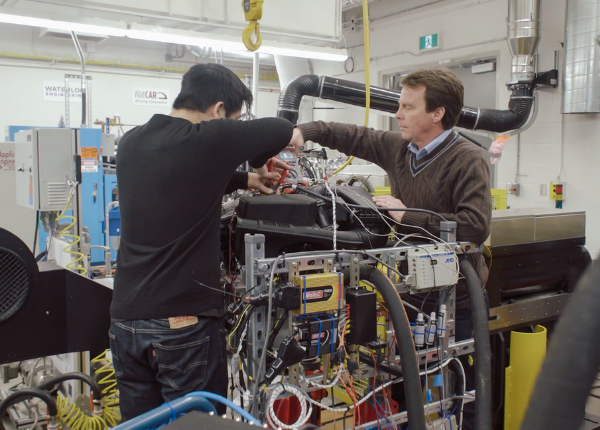 Student works with teacher on automotive-related machine