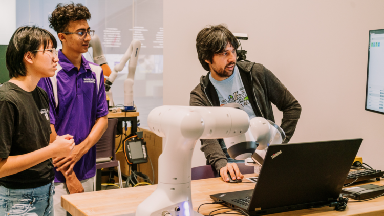 Two UWaterloo engineering students looking at laptop with expert