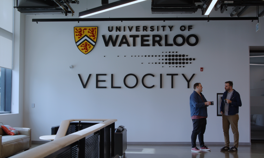 Two people talking in front of the Velocity logo